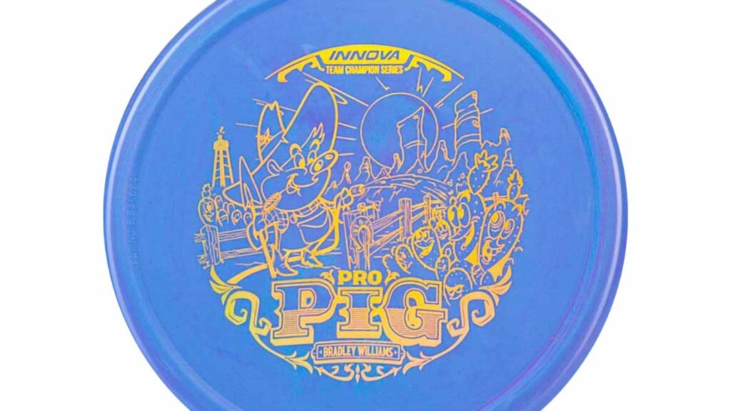 An Innova Pro Pig blurple disc with holographic stamp. The disc contains an image depicting a pig cartoon situated in a desert environment with cacti and rocks in its surroundings.