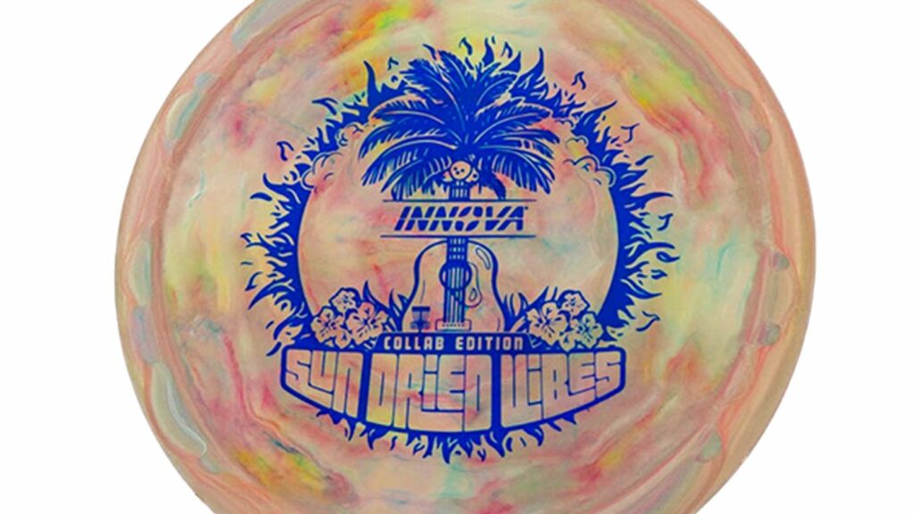 Innova Test-Pro Pig (Sun Dried Vibes) Galaxy color disc (beige, orange-ish, green) w/Blue Stamp. The image shown on the disc has summery atmosphere with its inclusion of coconut trees, Hibiscus flowers, and a guitar, evoking a tropical and musical ambiance.